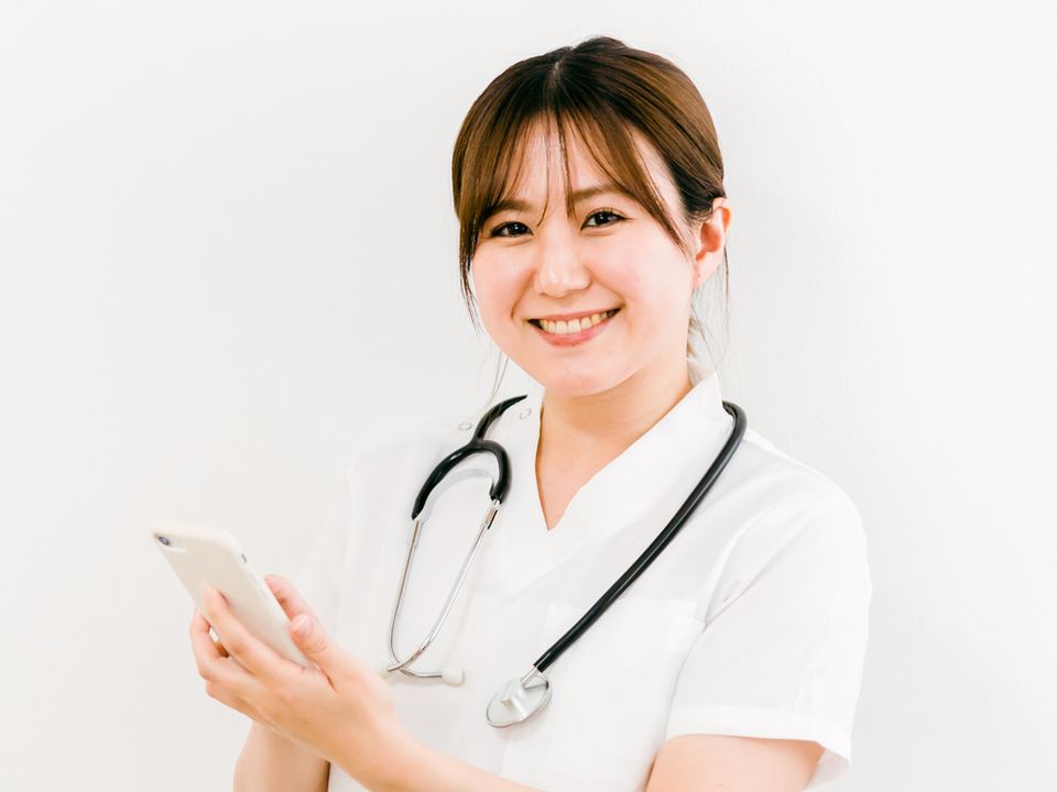 スマートフォンを手にほほえむ医師