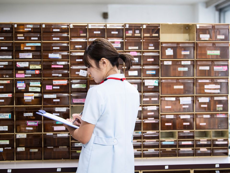 薬品棚の前で在庫を確認する看護師